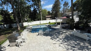 En trädgård med en pool, utemöbler och ett vitt staket.