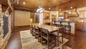 A spacious kitchen with wooden cabinets, a central island, and a stone fireplace. - Luxury 4,200 sq ft duplex perched above Breckenridge overlooking the 10-mile range! (Breckenridge)