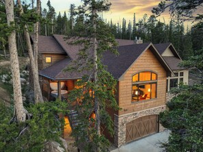 Une cabane en rondins avec des fondations en pierre, une grande fenêtre et un espace visible où se trouve un jacuzzi.