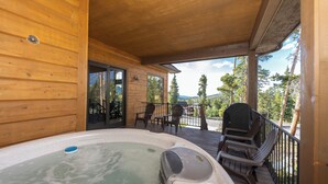 A wooden deck with a hot tub, outdoor seating, and a view of trees and mountains. - Luxury 4,200 sq ft duplex perched above Breckenridge overlooking the 10-mile range! (Breckenridge)