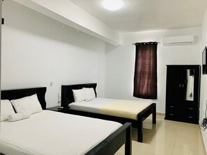 Ein Hotelzimmer mit zwei Betten, einem Kleiderschrank und einer Klimaanlage.