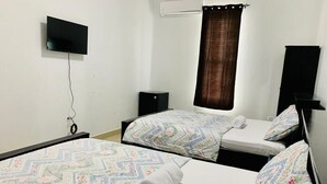 Un dormitorio con dos camas, un televisor en la pared y una ventana con cortina.