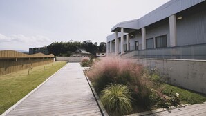 Un edificio moderno con una galería techada y un área verde con plantas.