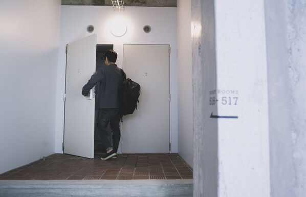 Una persona entrando en una habitación con una puerta marcada con el número "517" y un letrero que indica "HABITACIONES".