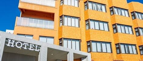 A hotel building with a modern design, featuring multiple balconies and large windows.