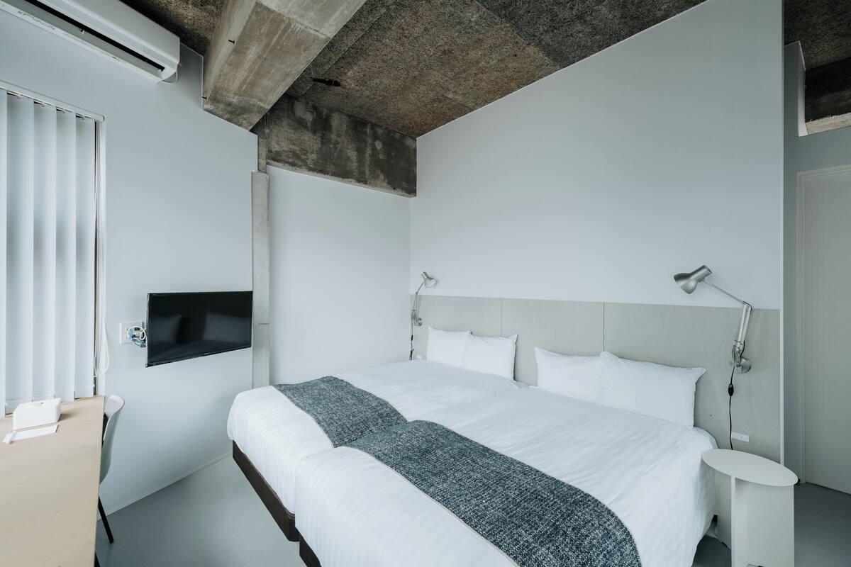 A modern hotel room with a large bed, a desk, and a TV mounted on the wall.