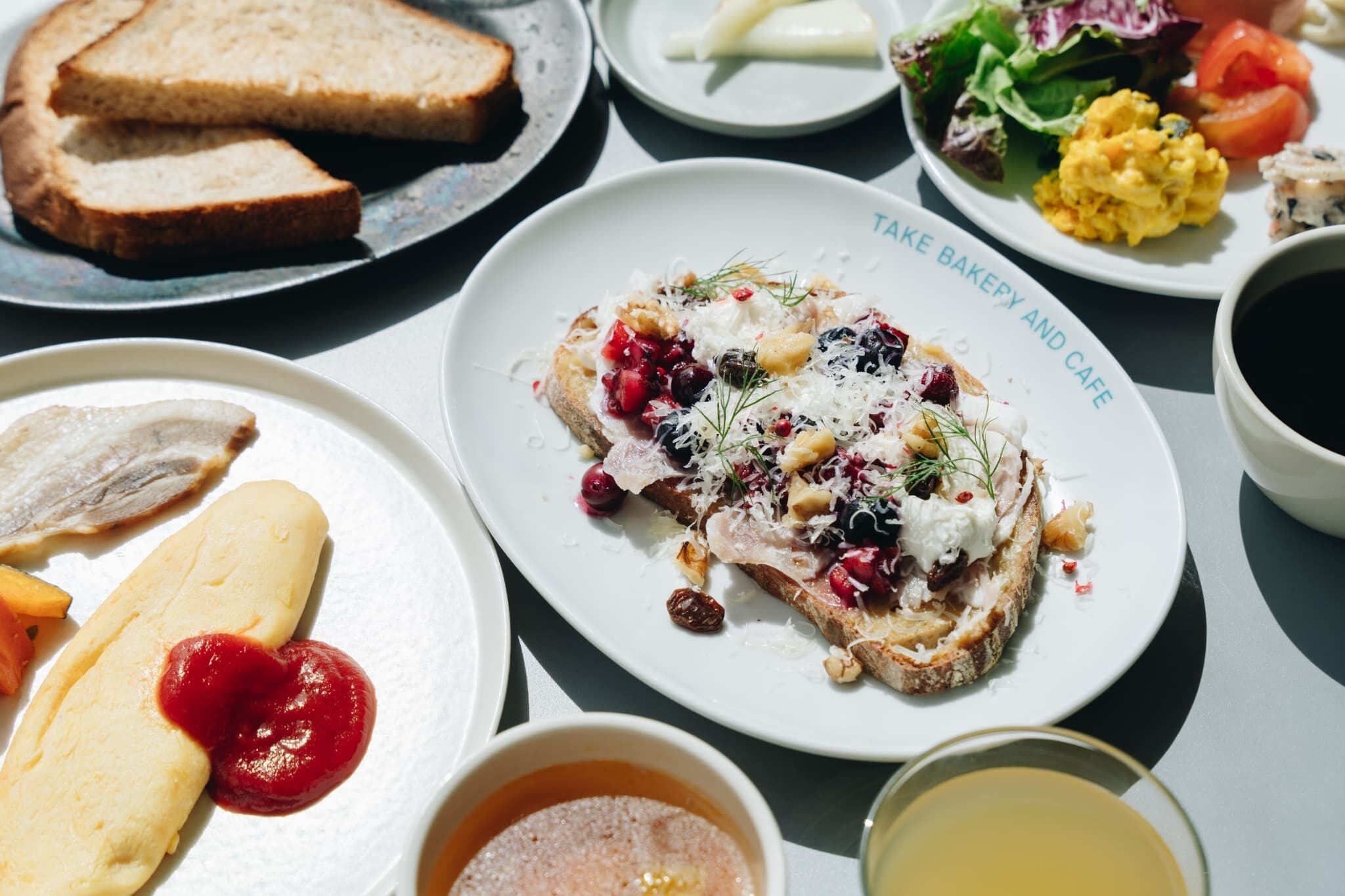A table with various breakfast items including toast, scrambled eggs, and a plate with a fish sandwich.