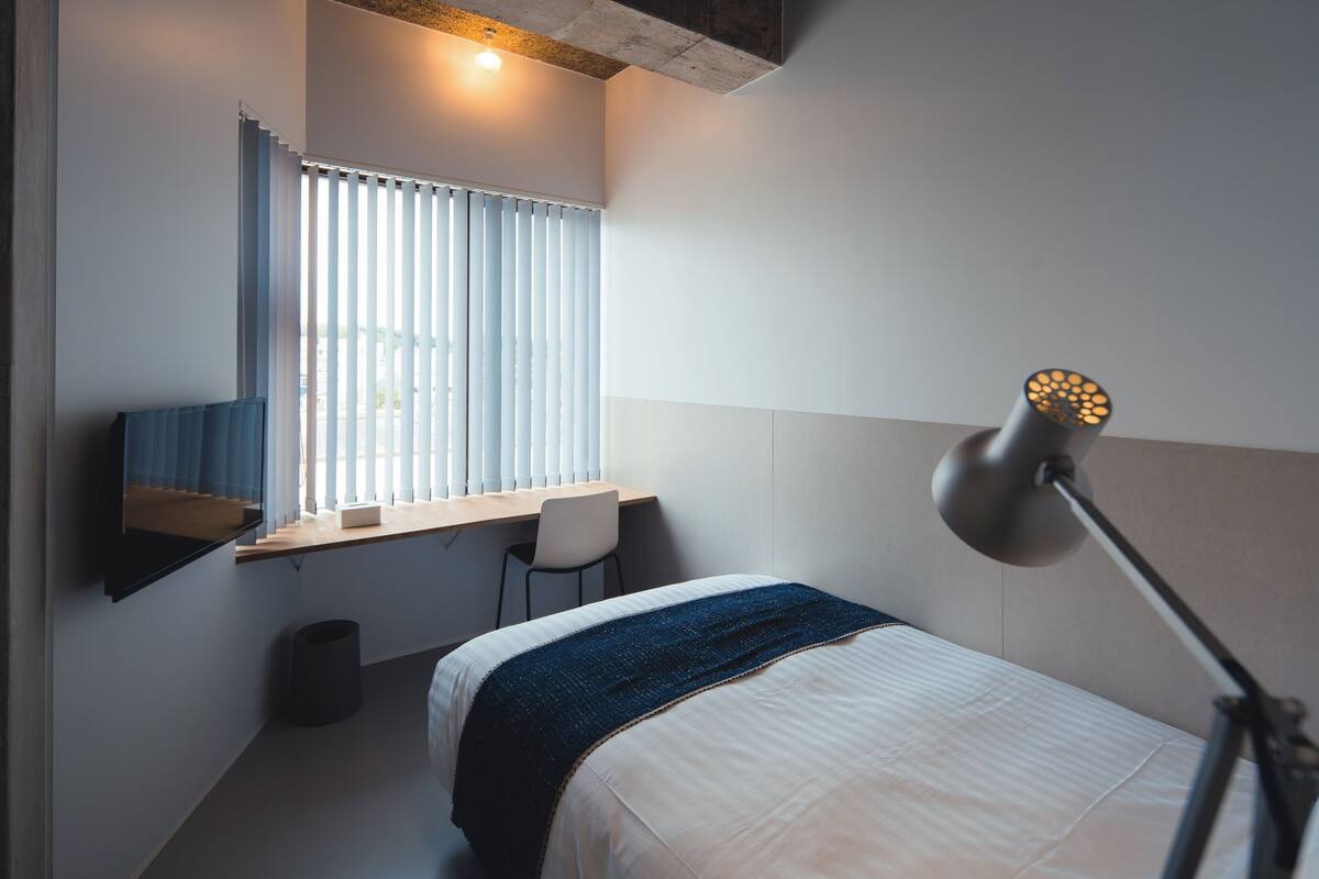 A modern hotel room with a bed, a desk, and a chair.