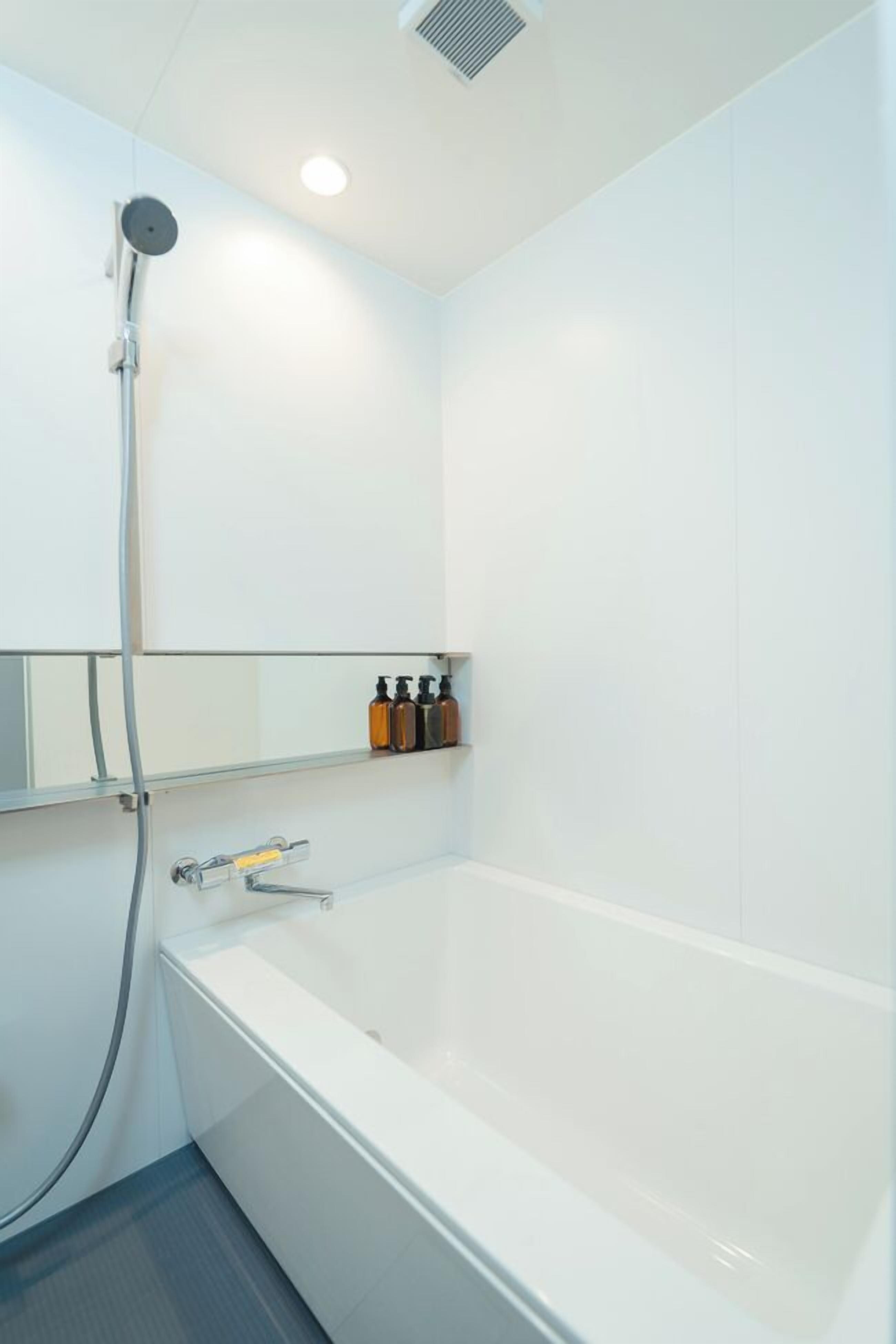 Une salle de bain moderne avec une baignoire blanche, une douchette à main et une étagère contenant des articles de toilette.