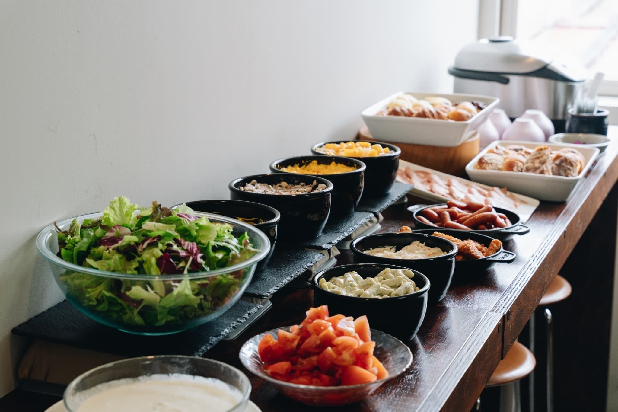 A buffet table with various dishes including salads, fruits, and other food items.