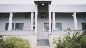Un edificio moderno con entrada central, ventanas amplias y techo plano.