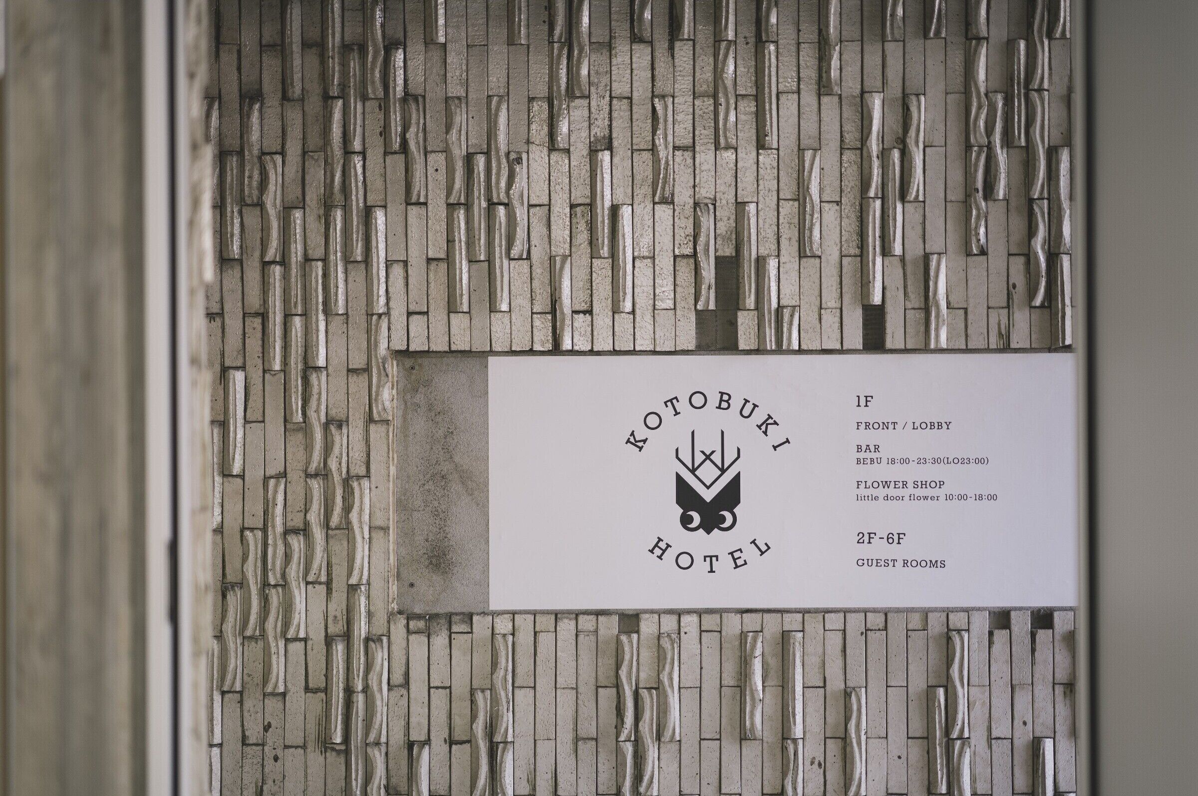 A hotel sign with a textured wall background and a white label listing room types and amenities.