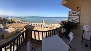 A balcony with a view of a beach, a table, chairs, and a potted plant. - My Sky • Wake to the Sea • Quiet Coastal Apartment + Private Beach (Hurghada , Al Aheya)