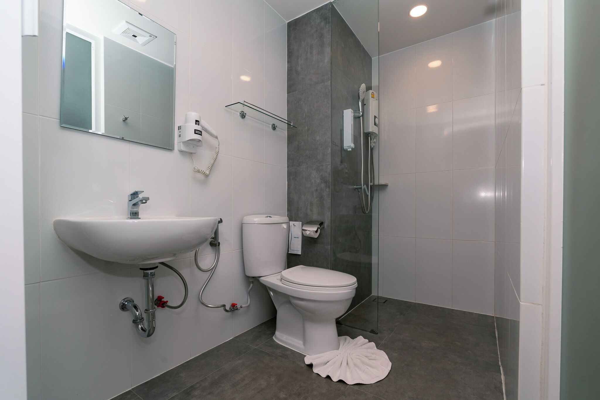 Un baño moderno con lavamanos, inodoro y ducha blancos.