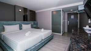 A modern hotel room with a large bed, a separate seating area, a bathroom with a glass door, and a kitchenette. - One Budget Chiangsaen (Chiang Saen)