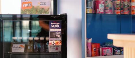 A beverage cooler with various drinks, a cash-only snack section, and a sign for a free special drink.
