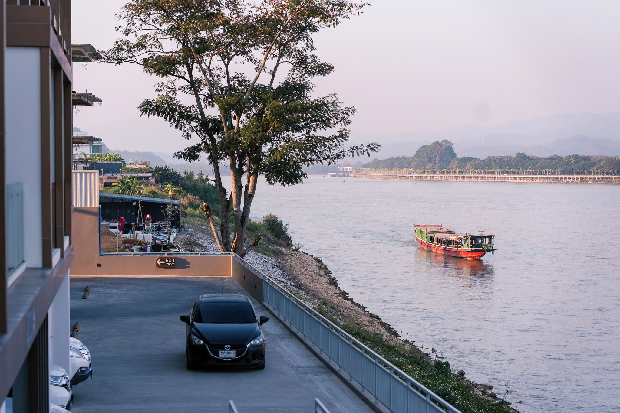 A car parked on a bridge with a view of a river and a boat.