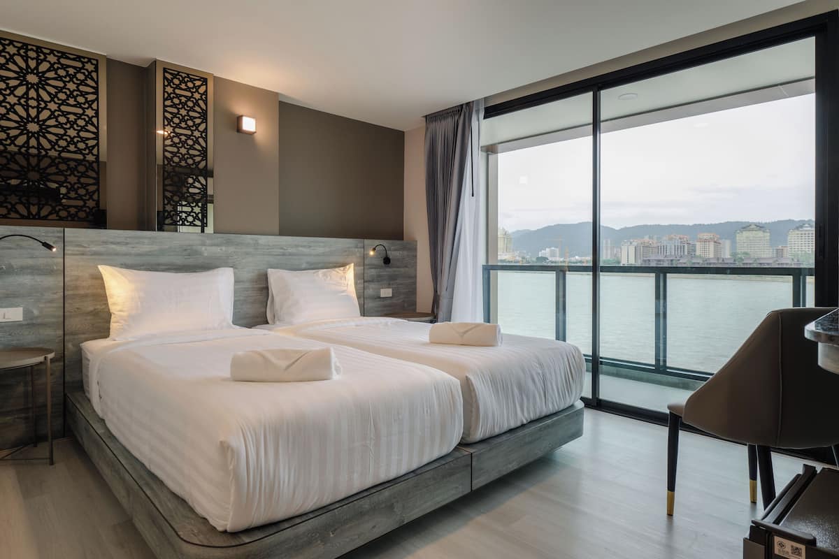 A modern hotel room with two beds, a large window with a city view, and a piano.