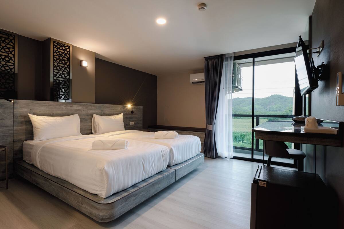 A modern hotel room with a large bed, a desk, and a view of the outdoors.