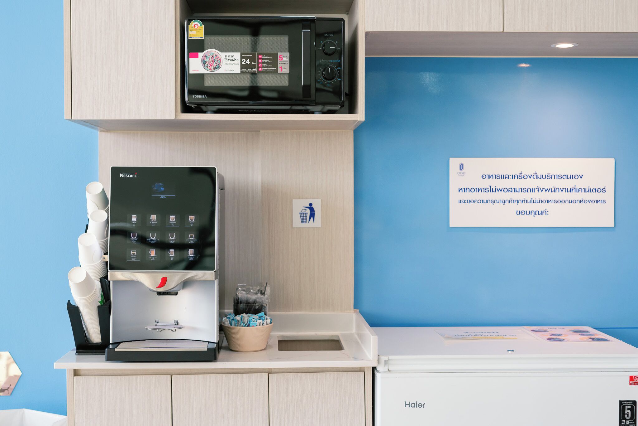 A kitchenette with a coffee machine, microwave, and a trash bin.