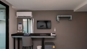 A modern office space with a desk, chair, air conditioning unit, television, and a small cabinet. - One Budget Chiangsaen (Chiang Saen)