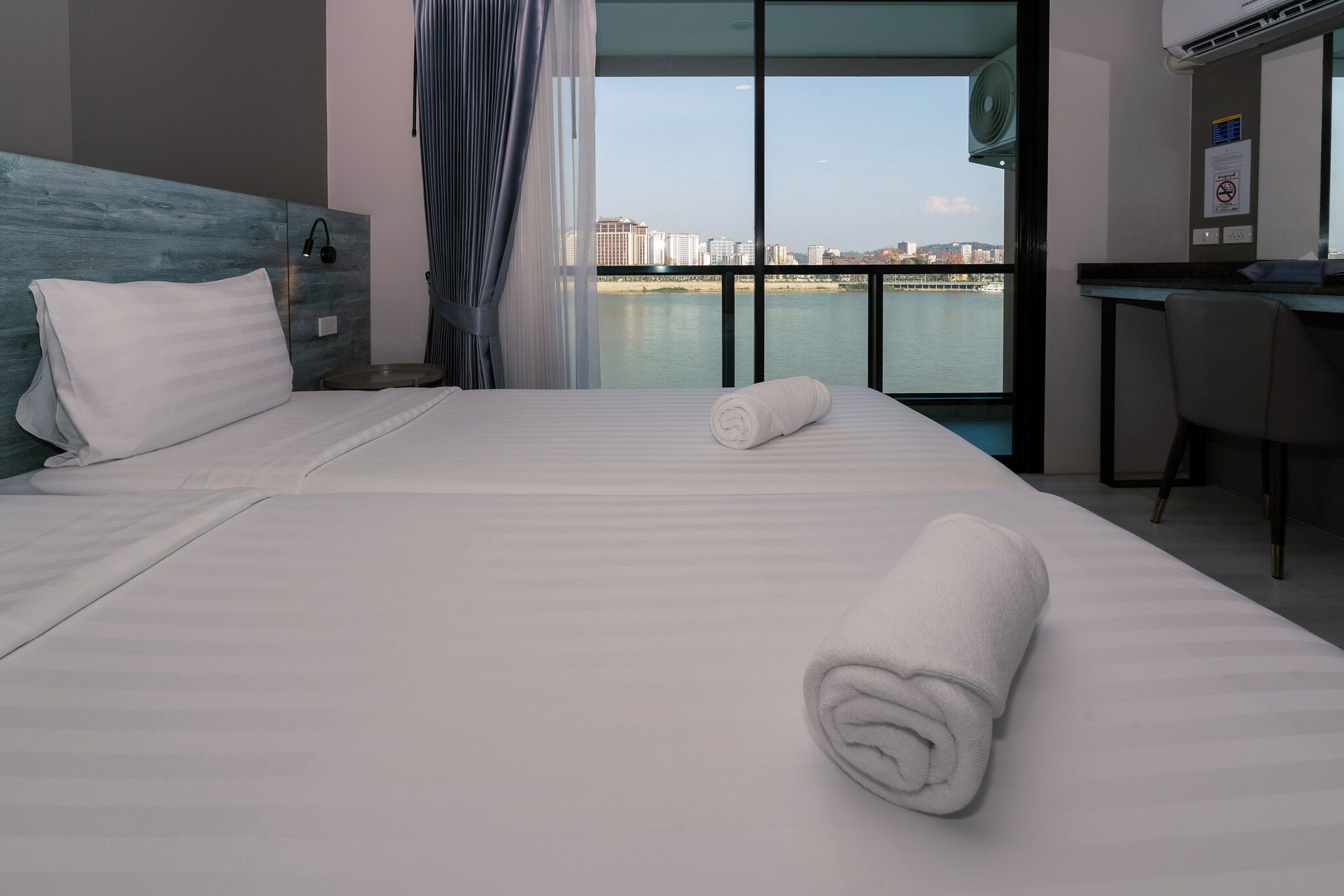 Une chambre d’hôtel avec un lit, un bureau, une chaise et une vue sur un plan d’eau et des bâtiments.