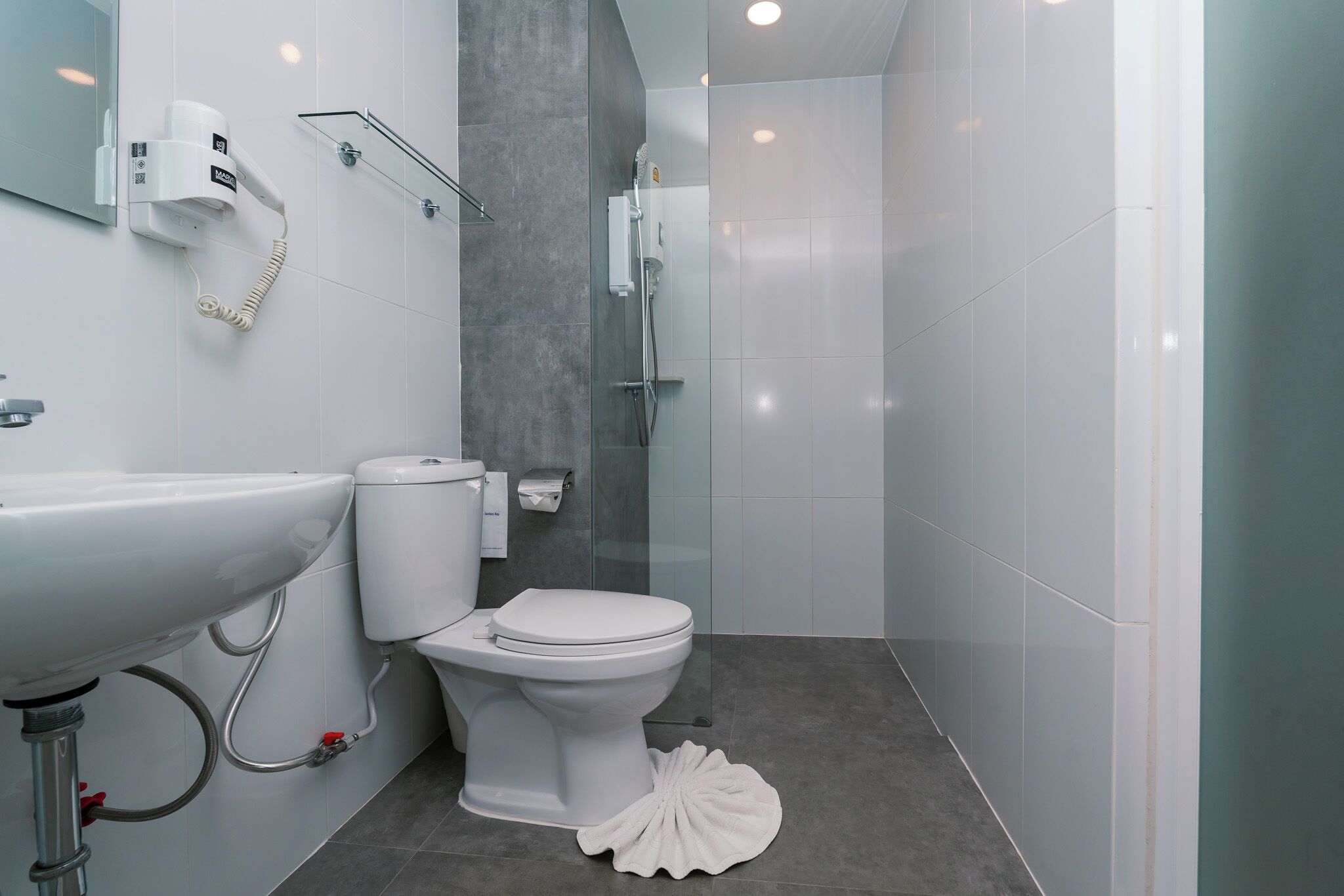 A modern bathroom with a white sink, toilet, and shower.
