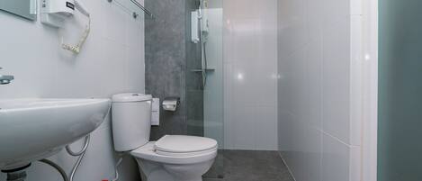 A modern bathroom with a white sink, toilet, and shower.