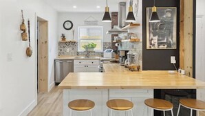 A modern kitchen with a wooden island, bar stools, pendant lights, and a view of the dining area. - Charming Farmhouse style w/cowboy pool in Fort Lauderdale (Fort Lauderdale)