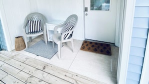 A covered porch with two chairs, a small table, a lantern, and a door with a window. - Cozy little lake cottage on Buck Lake!  (Vandalia)