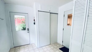 Un pasillo con suelo de baldosas, una puerta con ventanal y un armario con puertas correderas.
