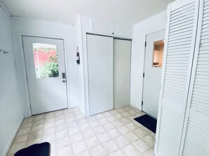 A hallway with a tiled floor, a door with a window, and a closet with sliding doors.