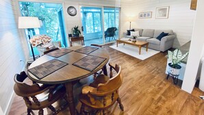 A spacious living room with a dining area, large windows, and a ceiling fan. - Cozy little lake cottage on Buck Lake!  (Vandalia)