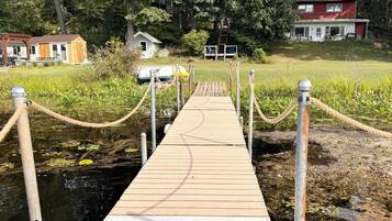 Un muelle de madera que lleva a una casa rodeada de árboles.