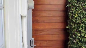 Une porte en bois avec une poignée en métal, située à côté d’un mur blanc percé d’une fenêtre.