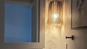 Une salle de bain dotée d’un grand miroir, d’un lavabo sur colonne, d’un luminaire suspendu et d’un meuble à pharmacie fixé au mur.