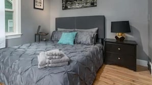 A bedroom with a bed, a nightstand, a lamp, and a window. - Cozy home in Bangor Maine (Bangor)