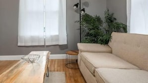 A living room with a beige sofa, a wooden coffee table, and a potted plant. - Cozy home in Bangor Maine (Bangor)