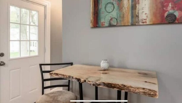 A dining area with a rustic wooden table, black metal chairs, and a white owl ornament. - Cozy home in Bangor Maine (Bangor)