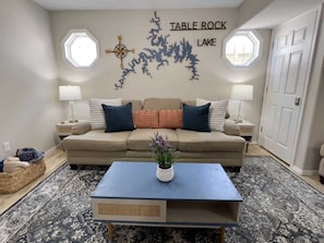 A living room with a sofa, a coffee table, and a wall decoration.