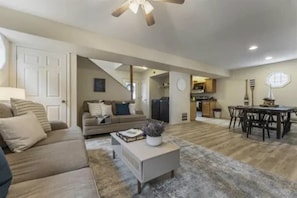 A living room with a sofa, coffee table, and dining area with chairs.