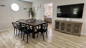 Un coin repas avec une table et des chaises en bois, un téléviseur et un meuble.
