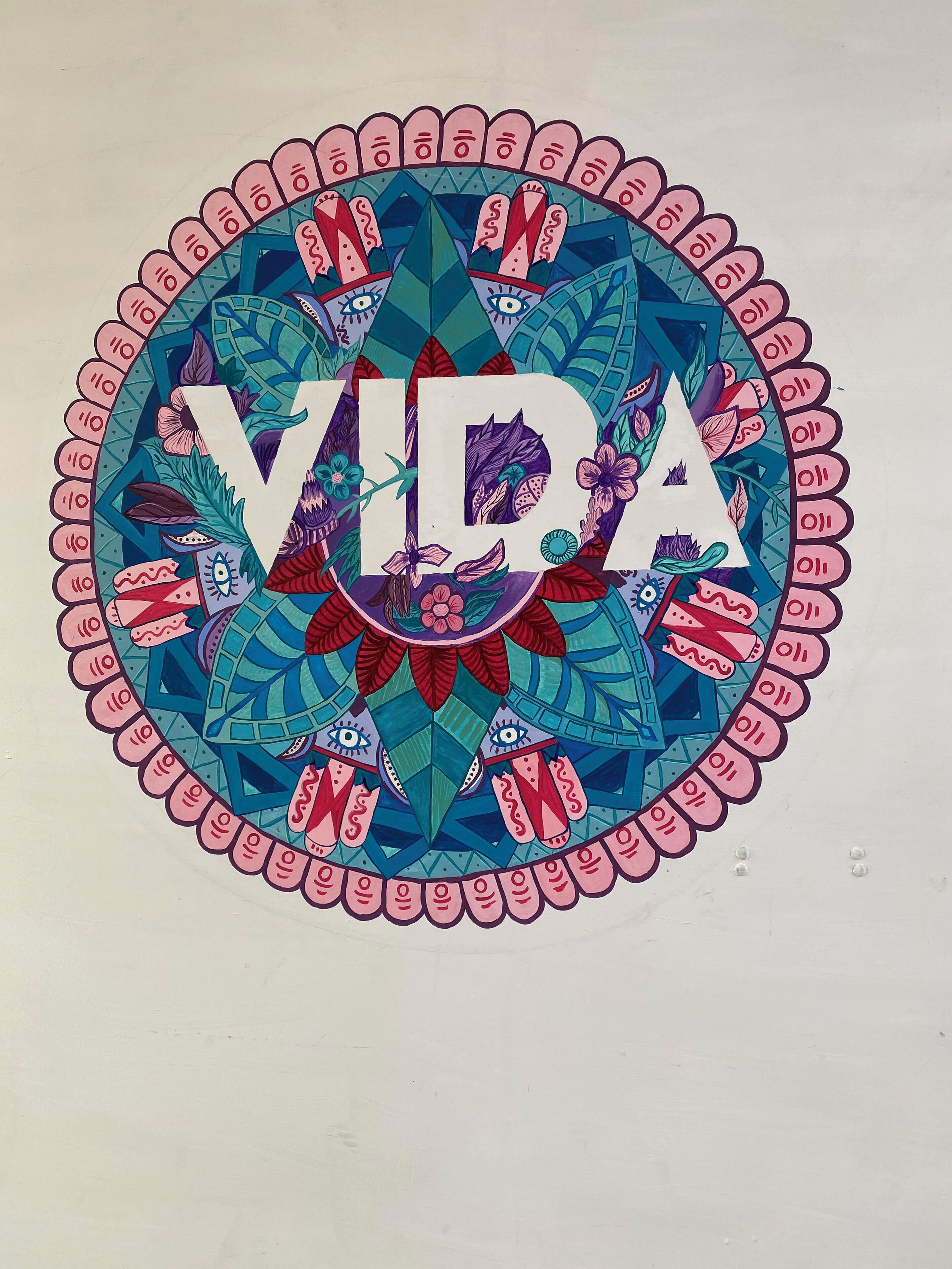 Un diseño circular con la palabra “VIVA” destacada en el centro, rodeada de patrones complejos y motivos florales.