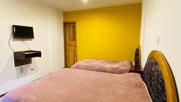 A room with a bed, a television mounted on the wall, and a door.
