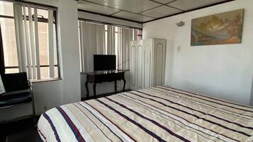Un dormitorio con una cama grande, televisión, armario y un cuadro en la pared.
