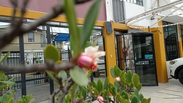 Une entrée d’immeuble avec une porte tournante, une voiture blanche garée et une enseigne bien visible indiquant « EMPULSE ».