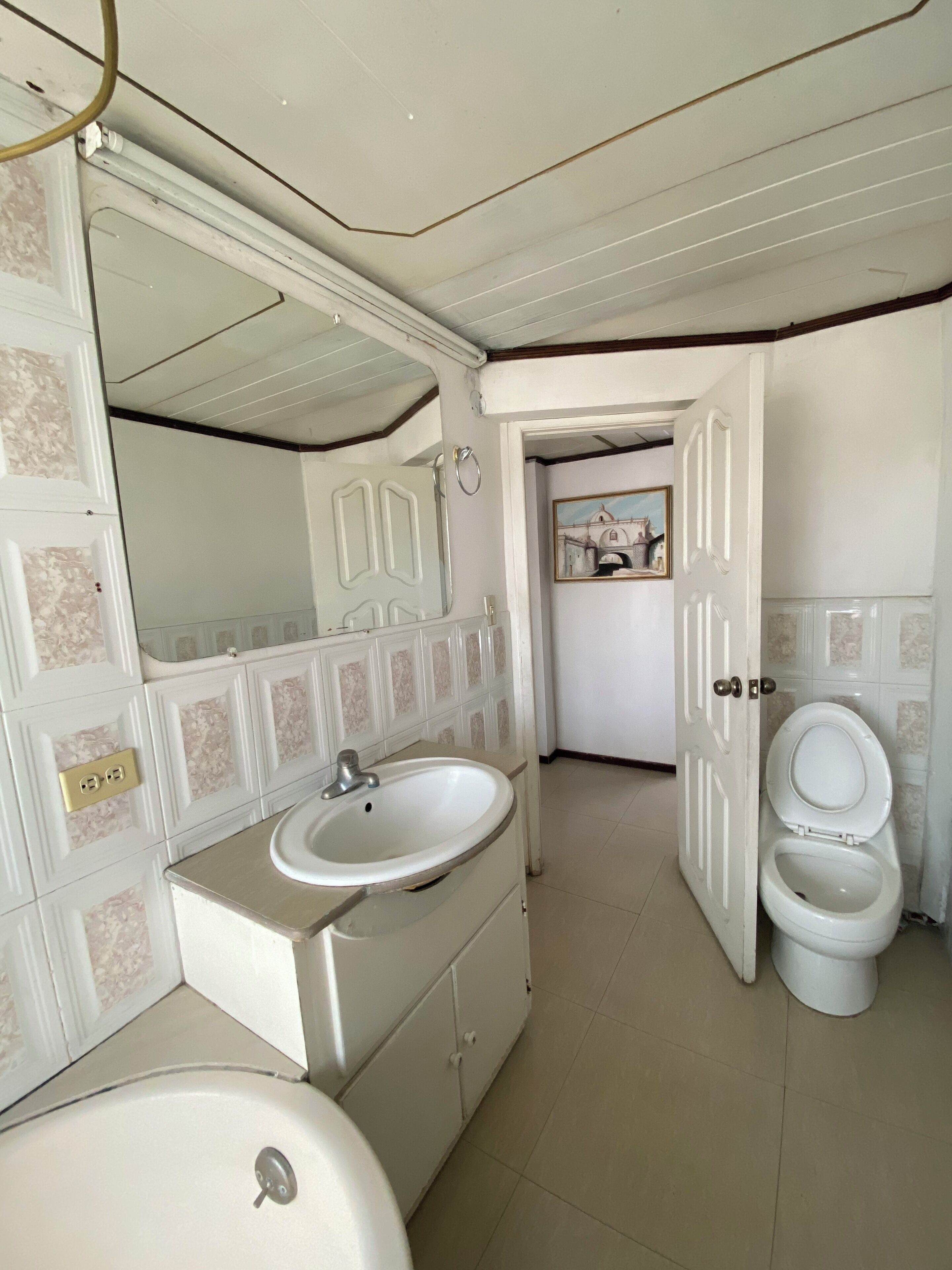A bathroom with a white sink, mirror, and toilet.