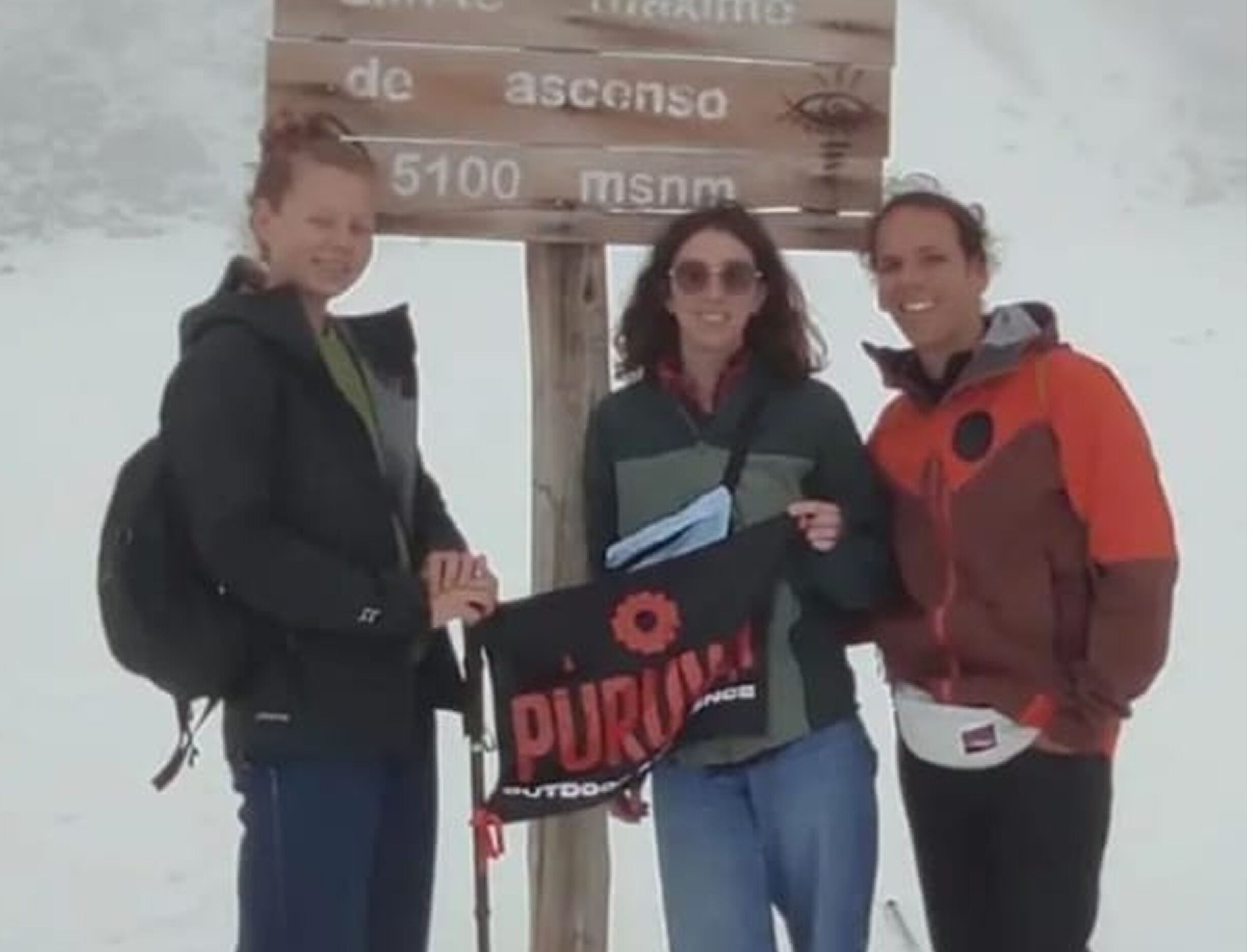 Tres personas de pie frente a un cartel con texto.