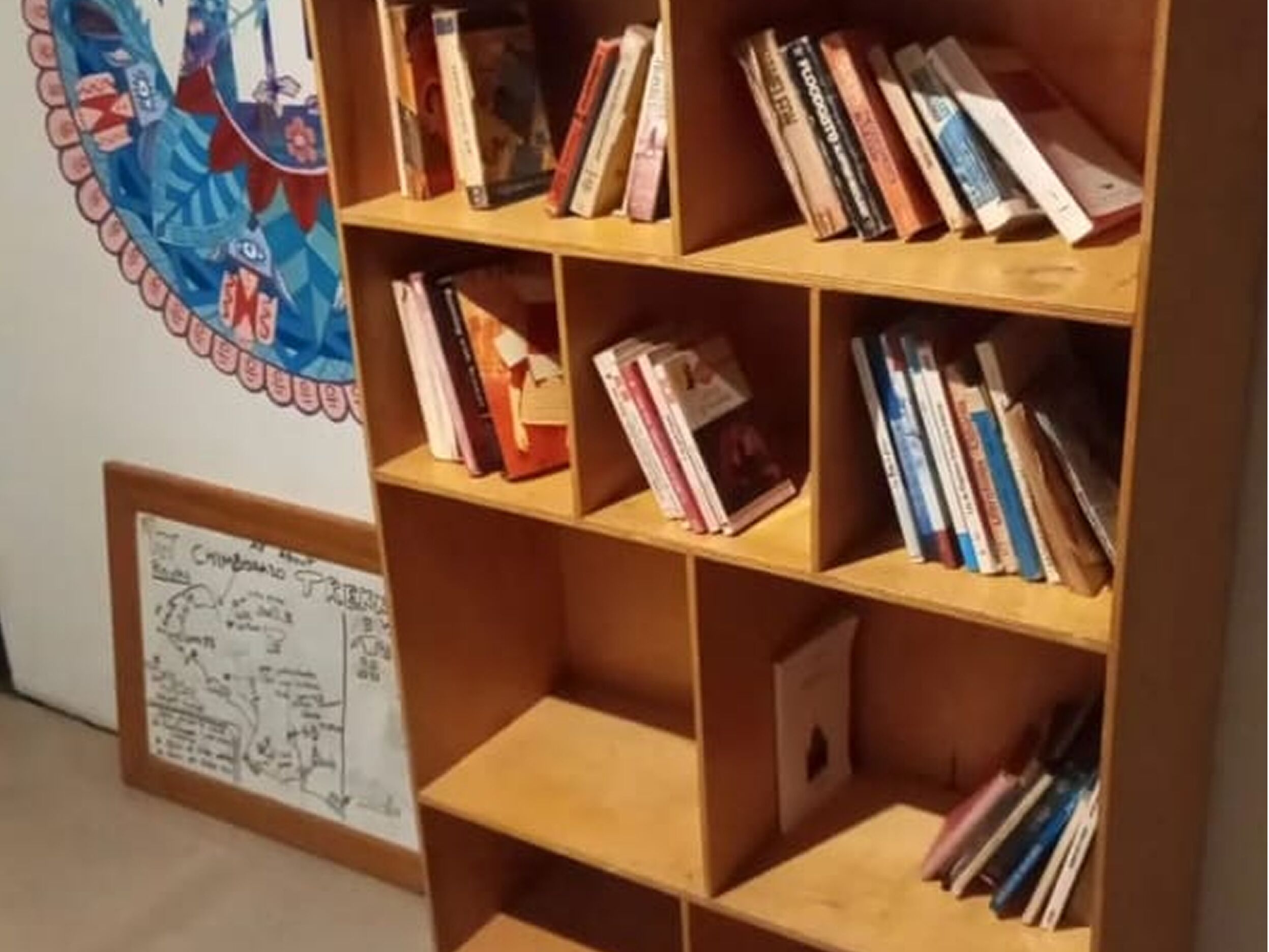 A bookshelf with various books and a framed architectural drawing on the wall.