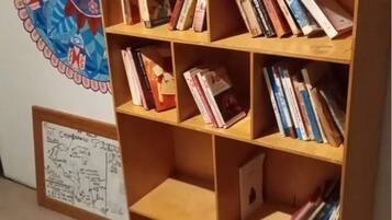 A bookshelf with various books and a framed architectural drawing on the wall.